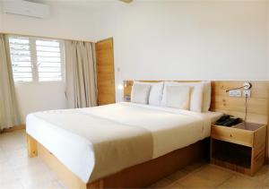 a bedroom with a large white bed with a lamp at Le Relax Hotel and Restaurant in Anse Royale