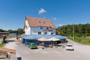 ein Gebäude mit Tischen und Sonnenschirmen davor in der Unterkunft Motel Evrica in Horezu