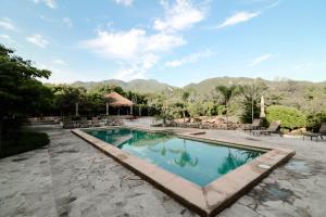 a swimming pool with a patio and mountains in the background at El Pedregal - Hotel en la Naturaleza in Álamos