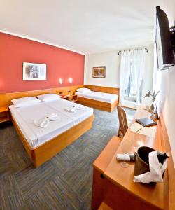 a hotel room with two beds and a desk at Hotel Kastil in Bol