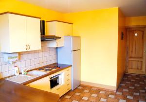 a kitchen with yellow walls and a white refrigerator at Vaivorykštė in Nida