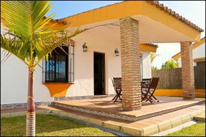 dom z patio z krzesłami i palmą w obiekcie Chalet con piscina privada w mieście Conil de la Frontera