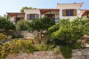 a house with trees in front of a stone wall at Betsanis Stafylos Apartments in Stafylos