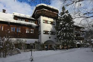 a large building with a snow covered tree in front of it at Romantikhotel Almtalhof in Grünau im Almtal