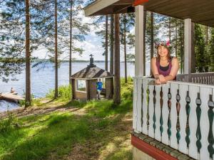 ヌルメスにあるHoliday Home Mäntylä by Interhomeの水辺の家の柵に腰掛けた女