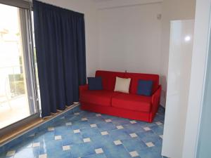 Sofá rojo sentado en una habitación con ventana en Apartment Appartamento 2 by Interhome, en Porto Badino