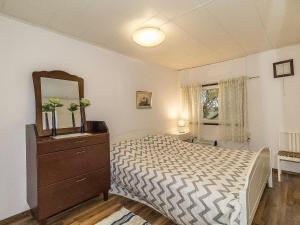 een slaapkamer met een bed, een dressoir en een spiegel bij Holiday Home Päivärinne by Interhome in Tallnäs