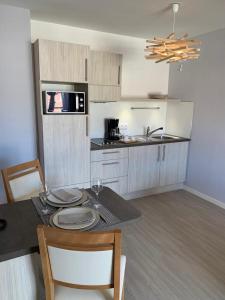 
a kitchen with a sink, stove, microwave and refrigerator at Résidence Services Seniors Domitys - Les Safrans in Dives-sur-Mer
