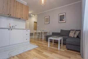ein Wohnzimmer und eine Küche mit einem Sofa und einem Tisch in der Unterkunft CR Apartament w sercu miasta Lipowa 1 in Białystok