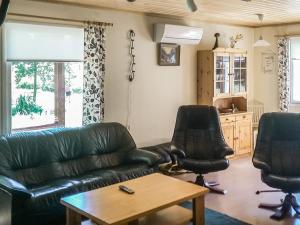a living room with a leather couch and two chairs at Holiday Home Långstrands stuga by Interhome in Långstrand +3 photos