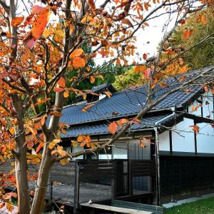 a building with a blue roof and a tree at Villa yamato in Kumamoto