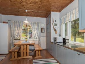eine Küche mit einem Tisch und einem Waschbecken sowie einige Fenster in der Unterkunft Holiday Home Lehtoniemi by Interhome in Tallnäs