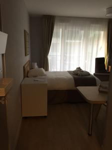 
a bedroom with a bed and a desk at Résidence Services Seniors Domitys - Les Safrans in Dives-sur-Mer
