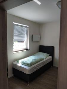 - une petite chambre avec un lit et une fenêtre dans l'établissement Haus Brückelsee, à Wackersdorf