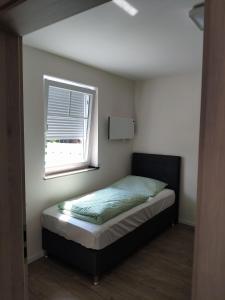 a small bedroom with a bed and a window at Haus Brückelsee in Wackersdorf