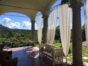 une terrasse couverte avec des rideaux blancs et une chaise sur la terrasse. dans l'établissement B&B Villa Natta, à Uggiate