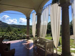 eine Veranda mit weißen Vorhängen und einem Stuhl auf einer Terrasse in der Unterkunft B&B Villa Natta in Uggiate