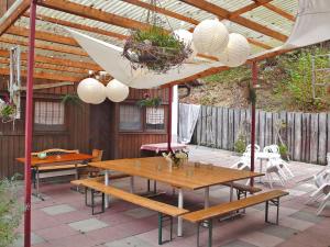 eine Terrasse mit Holztischen, Stühlen und einem Sonnenschirm in der Unterkunft Studio La Bergerie by Interhome in Ocourt