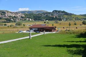 un campo de hierba con un edificio en el fondo en Rifugio Le Chevalier, en Roccaraso