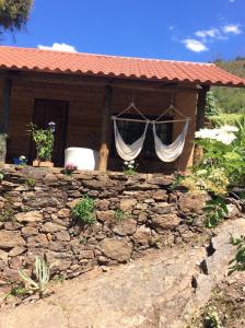 una casa con una pared de piedra y una ventana con cortinas en Unique Tiny House with Natural Building Techniques en Figueiró dos Vinhos