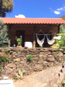 a house with a stone wall in front of a building at Unique Tiny House with Natural Building Techniques in Figueiró dos Vinhos