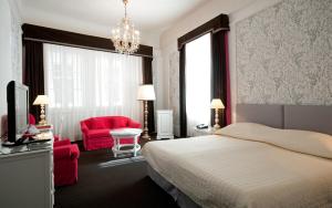 a bedroom with a bed and a red chair at Hotel König von Ungarn in Vienna