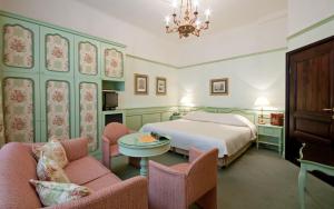 a bedroom with a bed and chairs and a chandelier at Hotel König von Ungarn in Vienna