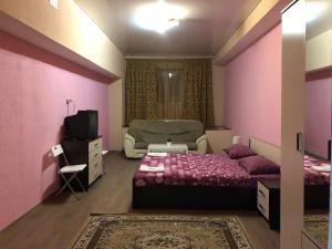 a bedroom with pink walls and a bed and a couch at Mini-Hotel Silver in Balashikha