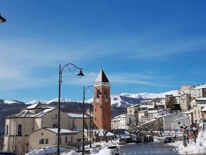 eine Stadt mit einem Uhrturm im Schnee in der Unterkunft La Casina di Montagna by Dimorra in Rivisondoli