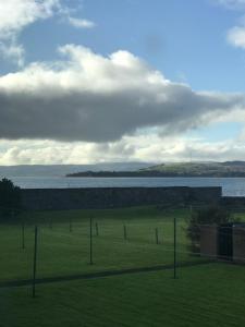 a field with a fence and a body of water at You deserve a staycation on the Firth of Clyde in Helensburgh
