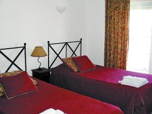 um quarto com duas camas com lençóis vermelhos e uma janela em Holiday Home Praia del Rey Golf by Interhome em Praia del Rei