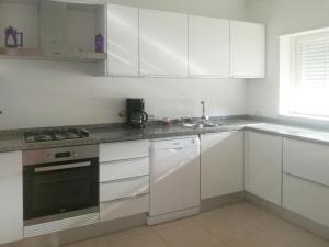 a white kitchen with white cabinets and a sink at Holiday Home Praia del Rey Golf Casa by Interhome in Casal da Lagoa Seca