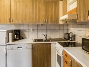a kitchen with white appliances and wooden cabinets at Holiday Home Vuokatinportti a7 by Interhome in Lahdenperä
