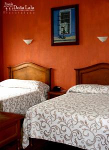 a bedroom with two beds and a picture on the wall at Hotel Posada Doña Lala in Tlacotalpan