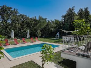 a pool with chairs and umbrellas in a yard at Holiday Home Forest Fairy by Interhome in Raša