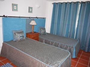 two beds in a room with blue curtains at Holiday Home Praia del Rey Golf Casa by Interhome in Casal da Lagoa Seca