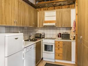eine Küche mit weißen Geräten und Holzschränken in der Unterkunft Holiday Home Vuokatinportti a7 by Interhome in Lahdenperä