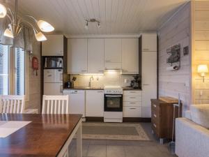 eine Küche mit weißen Schränken und einem Tisch im Zimmer in der Unterkunft Holiday Home Hil-lak-ka ii as 7 by Interhome in Äkäslompolo