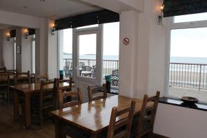 a dining room with tables and chairs and a view of the ocean at Gwesty Ty Newydd in Aberdaron