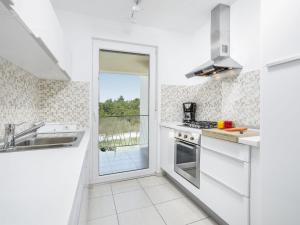 a white kitchen with a view of a balcony at Holiday Home Forest Fairy by Interhome in Raša