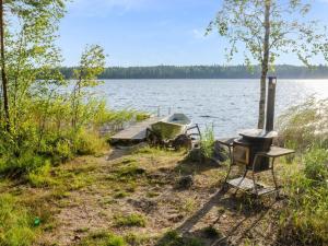 a picnic table and a boat on the shore of a lake at Holiday Home Kissankello by Interhome in Ahmovaara