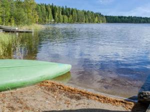 a green canoe sitting on the shore of a lake at Holiday Home Kanerva by Interhome in Ahmovaara