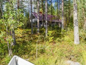 a house in the woods with a boat in the foreground at Holiday Home Metsätähti by Interhome in Ahmovaara