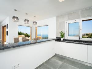 a white kitchen with windows and a view of the ocean at Apartment Miramar by Interhome in Moraira +18 photos