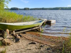 a green boat on the shore of a lake at Holiday Home Kissankello by Interhome in Ahmovaara