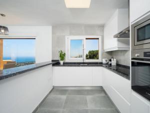 een keuken met witte werkbladen en een raam met uitzicht op de oceaan bij Apartment Miramar by Interhome in Moraira