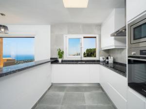 a kitchen with white counters and a window with the ocean at Apartment Miramar by Interhome in Moraira