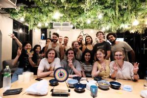 een groep mensen die poseren voor een foto aan een tafel bij Wayha Hostel Don Mueang Airport in Bangkok