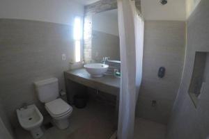 a bathroom with a toilet and a sink and a mirror at Casa en El Quijote Club de Chacras, La Barra, Punta del Este. in Maldonado +19 photos