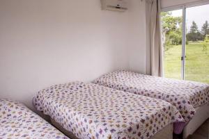 two twin beds in a room with a window at Casa en El Quijote Club de Chacras, La Barra, Punta del Este. in Maldonado